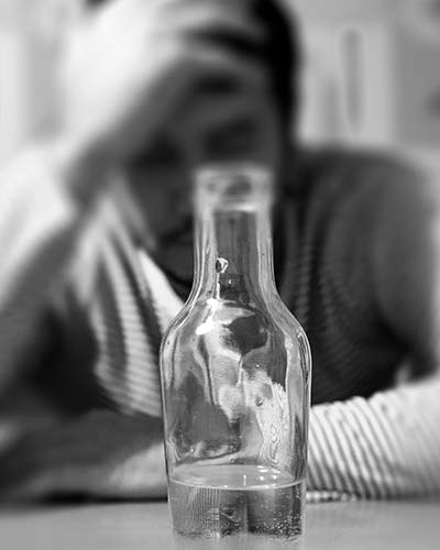бутылка с алкоголем на фоне грустного мужчины